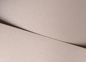 Paper background with satin pearlescent texture. Matte folded surface with diagonal overlap, pale photo