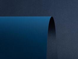 Paper background with matte texture. Curved smooth sheets in navy, midnight blue, and deep blue photo