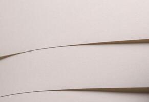 Paper background with matte texture. Curved folded surface in ivory, sand, and cool beige tones, photo