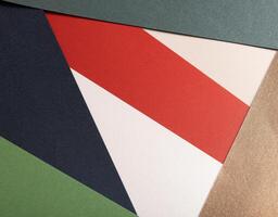 Paper background with matte texture. Layered geometric triangles in crimson red, pastel green, photo
