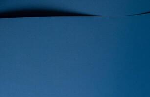 Paper background with matte texture. Curved wave and curl shape in ocean blue, royal blue, and deep photo