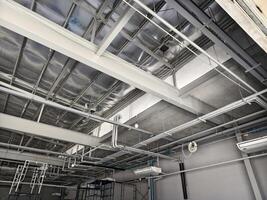 The ceiling of a large building under construction an extensive network of pipes photo