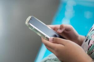 Close up view of a little girl's hand using a smartphone in public transportation photo