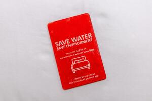 Message about save water and save the environment on a card above the hotel bed photo