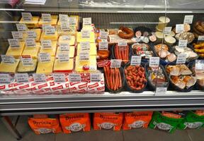 Dnipro, Ukraine - April 26, 2025 - Cheese blocks and smoked sausages displayed in supermarket deli counter. Concept of grocery shopping, delicious cheese selection, smoked meat variety photo