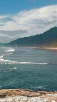 Coastal beach with waves and distant rocky cliffs. video