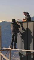 Workers constructing a modern rooftop, scenic winter mountains with snowy peaks, video