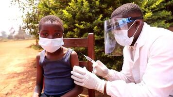 an African doctor injects the vaccine to a child. Coronavirus protection in africa concept. video