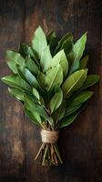 A bunch of green leaves tied to a wooden table photo