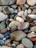 High-quality close-up photo of colorful smooth pebbles on a beach. Natural rounded stones with detailed textures and soft daylight. Perfect for backgrounds, nature themes, or design use.