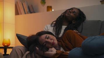 Quiet intimacy between two women as one rests her head on her partner's lap wrapped in warmth, stillness, and the soft glow of a peaceful evening at home. video