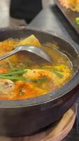 A simmering pot of Sundubu Jjigae, a traditional Korean spicy tofu soup. Packed with soft tofu, mushrooms, vegetables, and a rich red broth, this dish radiates warmth and authentic Korean flavors. video
