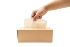Hand taking Brown tissue paper box isolated on white background. Copy space for text. Nice natural cardboard box of paper tissue. photo