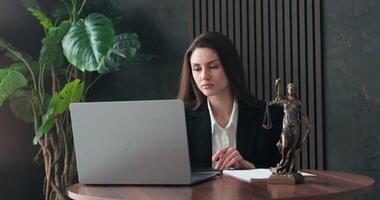 A lawyer or attorney reviews client files, interview transcripts, evidence with a laptop computer in a modern office. Concepts of law and legal services video