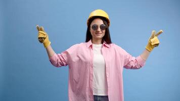 Woman in yellow helmet and gloves pointing and gesturing against blue background video