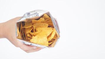 Man hand holds an opened foil bag of yellow nachos chips isolated on white background photo