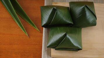 Kue Bugis, popular traditional dessert snack in Indonesian wrap in green leaves called on wooden platter photo