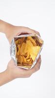 Man hands holding an opened foil bag of yellow nachos chips isolated on white background photo