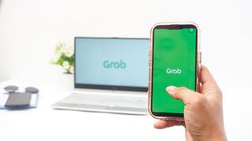 Yogyakarta, Indonesia, 2025 -Man hand with smartphone that shows front page of Grab application, on-demand service platforms from Indonesia, on the screen isolated on white background photo