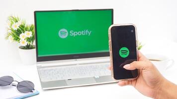 Yogyakarta, Indonesia, 2025 - Hand holding smartphone that shows front page of Spotify, digital audio streaming platform application on the screen isolated on white background photo