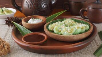 Kue Lupis, legend of traditional Indonesia rice cake snack with grated coconut and palm sugar syrup, on pottery tray photo