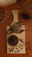 Top view of cloves spice with dried leaves on wooden platters isolated on wooden texture background photo