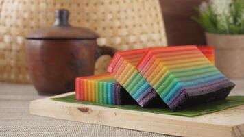 Kue Lapis, classic traditional Indonesia rainbow layer cake snack on wooden platter against rustic background photo