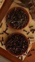 Top view of dried cloves spice with dried leaves on wooden platters isolated on wooden texture background photo