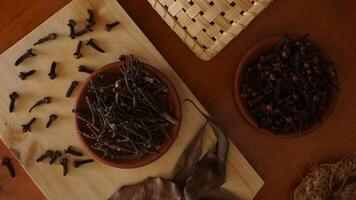 Top view of cloves spice on wooden platters isolated against wooden texture background photo