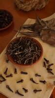 Cloves spice with dried leaves on wooden platters isolated on wooden texture background photo