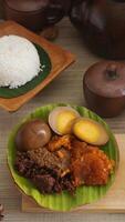 Gudeg, a specialty traditional Javanese dish from Yogyakarta, Indonesia, made primarily from young unripe jackfruit or nangka with several side dishes and a plate of rice photo