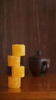 Stack of yellow rock sugar cubes isolated against wooden texture background photo