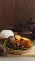 Gudeg, a delicious traditional Javanese dish from Yogyakarta, Indonesia, made primarily from young unripe jackfruit or nangka with several side dishes and a plate of rice photo