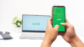Yogyakarta, Indonesia, 2025 -Hand with smartphone that shows front page of Grab application, on-demand service platforms from Indonesia, on the screen isolated on white background photo