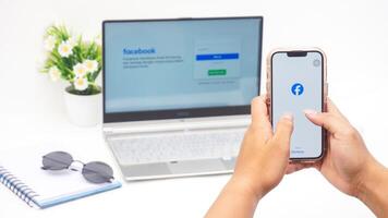 Yogyakarta, Indonesia, 2025 -Man hand using smartphone that shows front page of Facebook, social networking service application on the screen isolated on white background photo