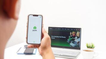 Yogyakarta, Indonesia, 2025 -Man using smartphone that shows front page of Gojek application, on-demand service platforms from Indonesia, on the screen isolated on white background photo
