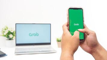 Yogyakarta, Indonesia, 2025 -Hand using smartphone that shows front page of Grab application, on-demand service platforms from Indonesia, on the screen isolated on white background photo