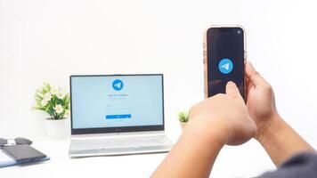 Yogyakarta, Indonesia, 2025 - Hand using smartphone that shows front page of Telegram, messaging and communication platform application on the screen isolated on white background photo