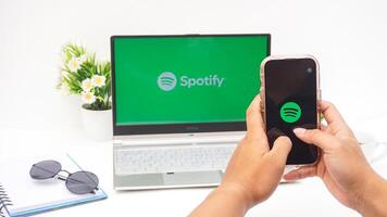 Yogyakarta, Indonesia, 2025 - Hand with smartphone that shows front page of Spotify, digital audio streaming platform application on the screen isolated on white background photo