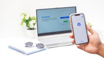 Yogyakarta, Indonesia, 2025 -Hand holding smartphone with front page of Facebook, social networking service application on the screen isolated on white background photo