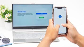 Yogyakarta, Indonesia, 2025 -Man hand holding smartphone that shows front page of Facebook, social networking service application on the screen isolated on white background photo