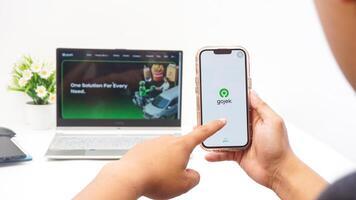 Yogyakarta, Indonesia, 2025 -Hand using smartphone that shows front page of Gojek application, on-demand service platforms from Indonesia, on the screen isolated on white background photo