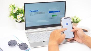 Yogyakarta, Indonesia, 2025 -Hand with smartphone that shows front page of Facebook, social networking service application on the screen isolated on white background photo