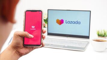 Yogyakarta, Indonesia, 2025 - Man with smartphone that shows front page of Lazada e-commerce platform application on the screen isolated on white background photo