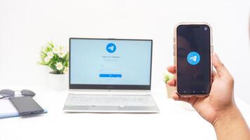 Yogyakarta, Indonesia, 2025 - Hand holding smartphone that shows front page of Telegram, messaging and communication platform application on the screen isolated on white background photo