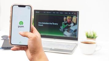 Yogyakarta, Indonesia, 2025 -Hand with smartphone that shows front page of Gojek application, on-demand service platforms from Indonesia, on the screen isolated on white background photo