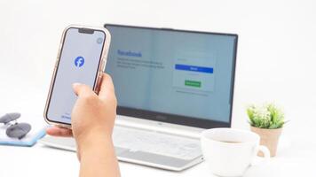 Yogyakarta, Indonesia, 2025 -Man hand with smartphone that shows front page of Facebook, social networking service application on the screen isolated on white background photo