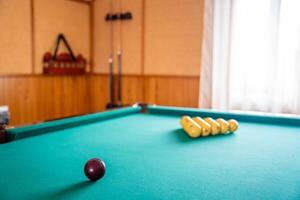 Initial billiard ball arrangement with white balls in a triangle and red cue ball ready for the break. Concept of indoor recreation and personal hobby space. High quality photo