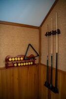 Home billiard setup with white balls, red cue ball, triangle rack, and cues neatly arranged. Concept of indoor recreation and personal hobby space. High quality photo