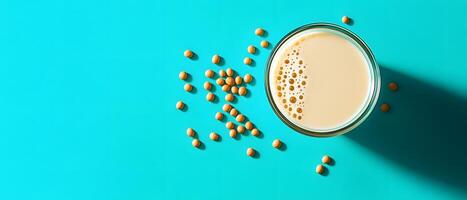 Glass of soy milk on vibrant turquoise background photo
